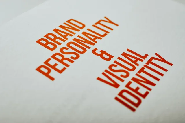 Close-up of 'Brand Personality & Visual Identity' text in red on white paper. Tone of voice på dansk: find brandets stemme